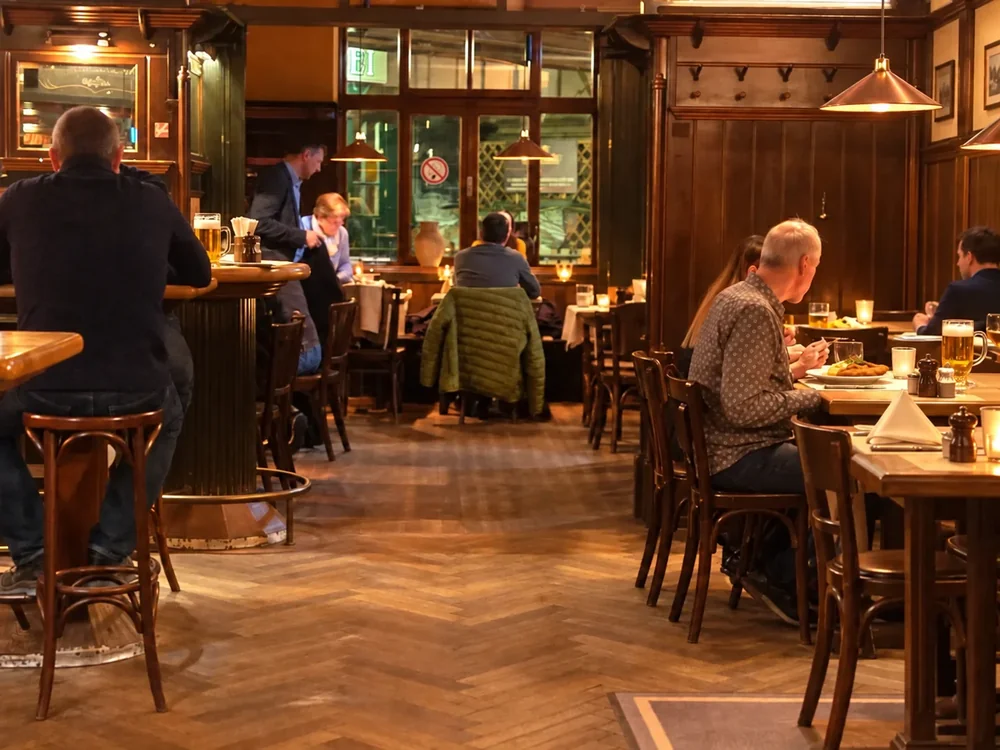 Gäste im warm beleuchteten, holzgetäfelten Gastraum des Fischerbräu