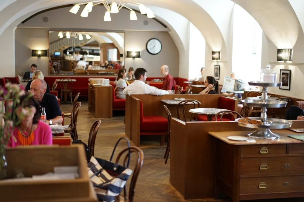 Kaffeehausgäste im hellen Gewölbe des Café Diglas im Schottenstift