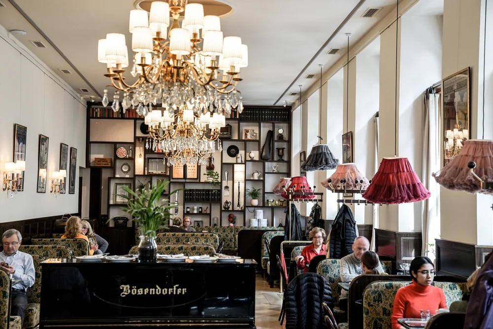 Kronleuchter, Klavier und Kaffeehaustische im Café Weimar