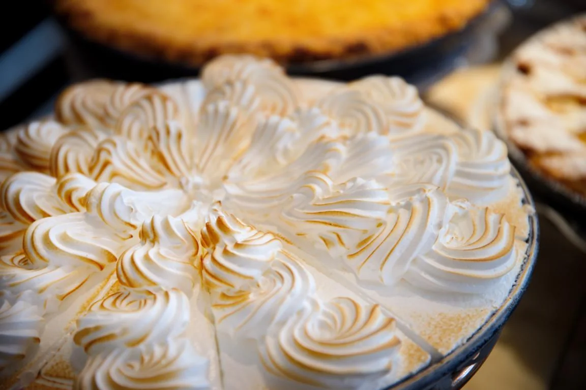 Sorgfältig aufgespritzte und goldbraun geflämmte Baiserspitzen auf einer Torte